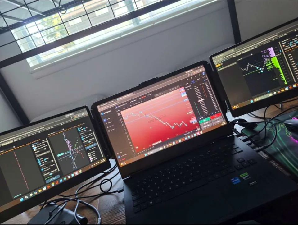 Laptop trader setup with two side monitors displaying live charts