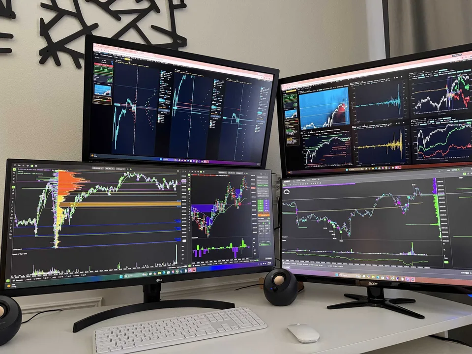 Four-monitor trader desk displaying charts and order-flow analytics